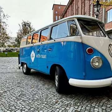 An orange VW camper cruises down a two-lane highway