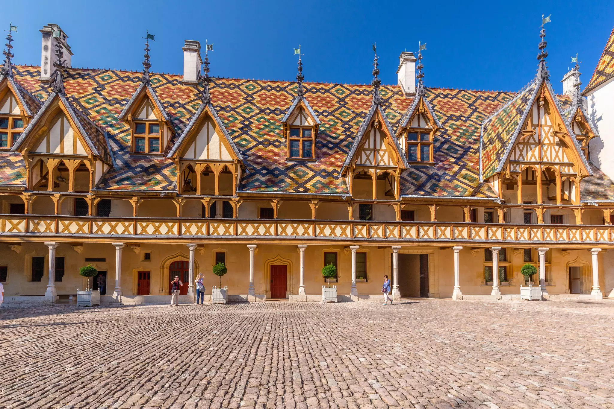 A cobbled courtyard surrounded by a chalet-style building with a detailed tiled roof.