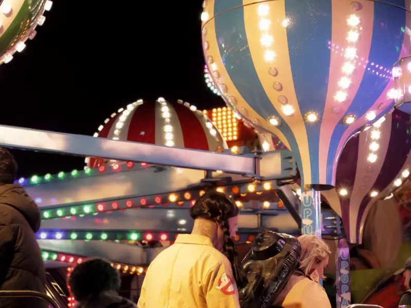 People board a ride at a theme park at night.