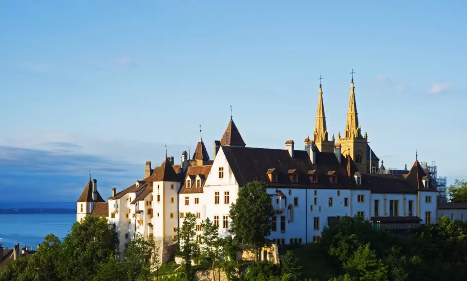 Neuchâtel castle's white walls and the twin spires of the collegiate church on a wooded hill above Lake Neuchâtel