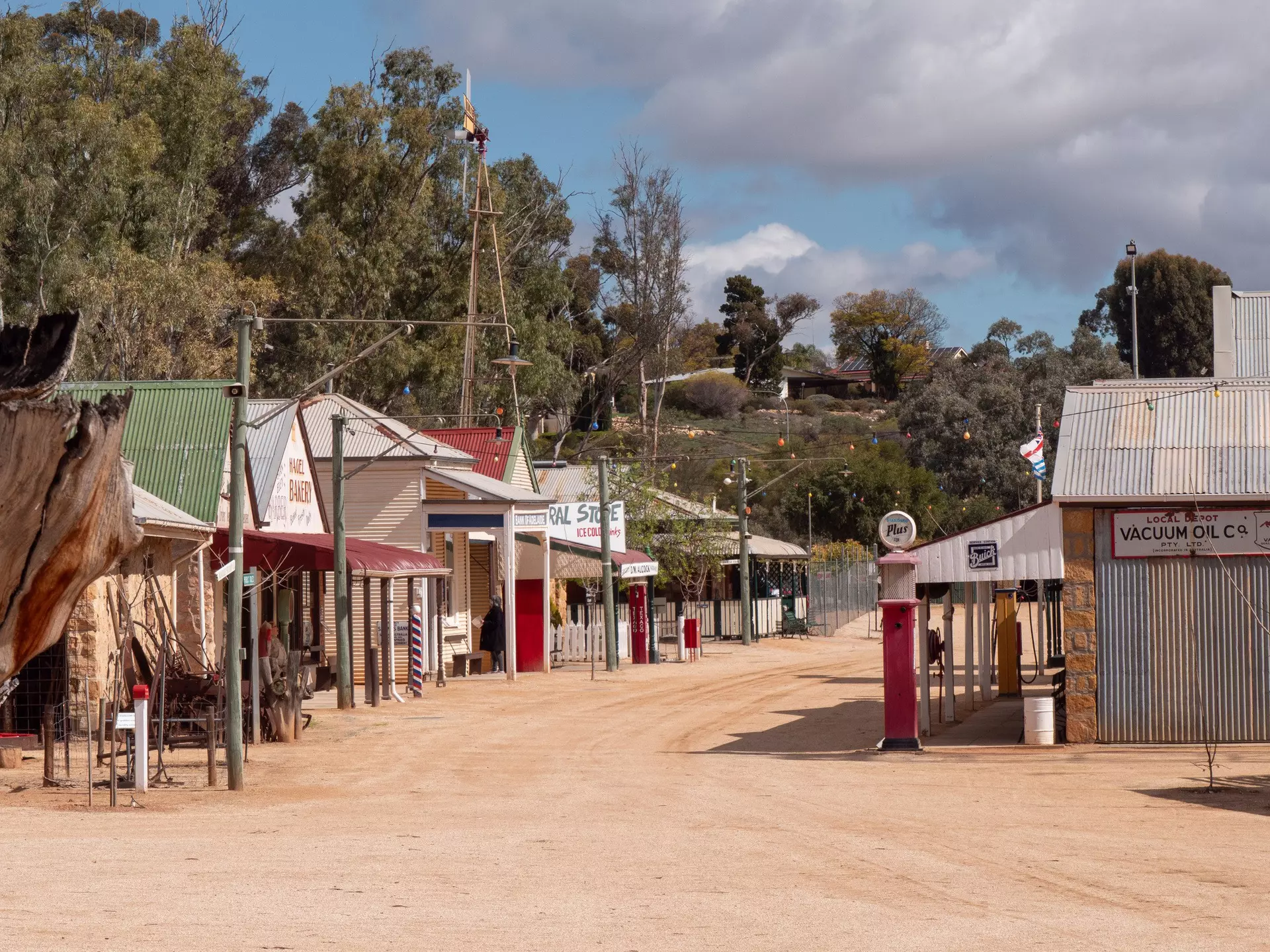 A dusty main street lined with restored shops and fuel pumps at Loxton Historical Village, showcasing Riverland life from the late 19th and early 20th centuries.