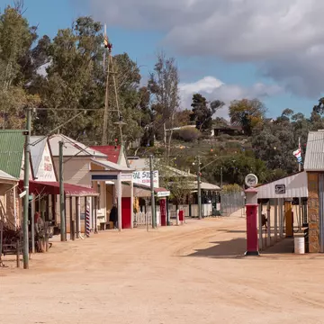 A dusty main street lined with restored shops and fuel pumps at Loxton Historical Village, showcasing Riverland life from the late 19th and early 20th centuries.