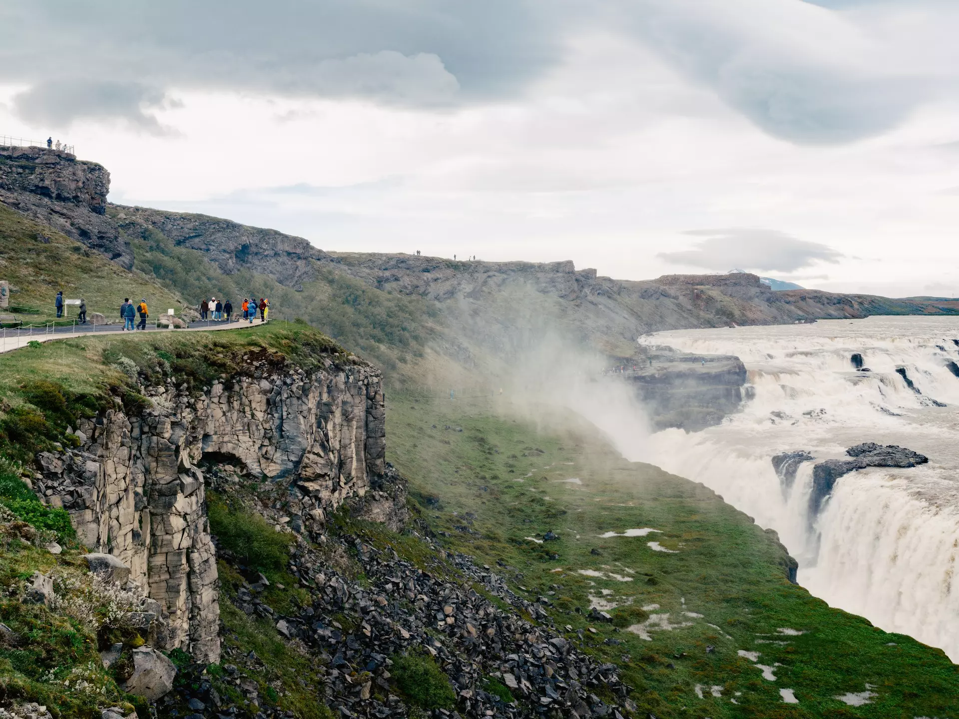 A powerful waterfall. People walk on the cliffs above to view it.