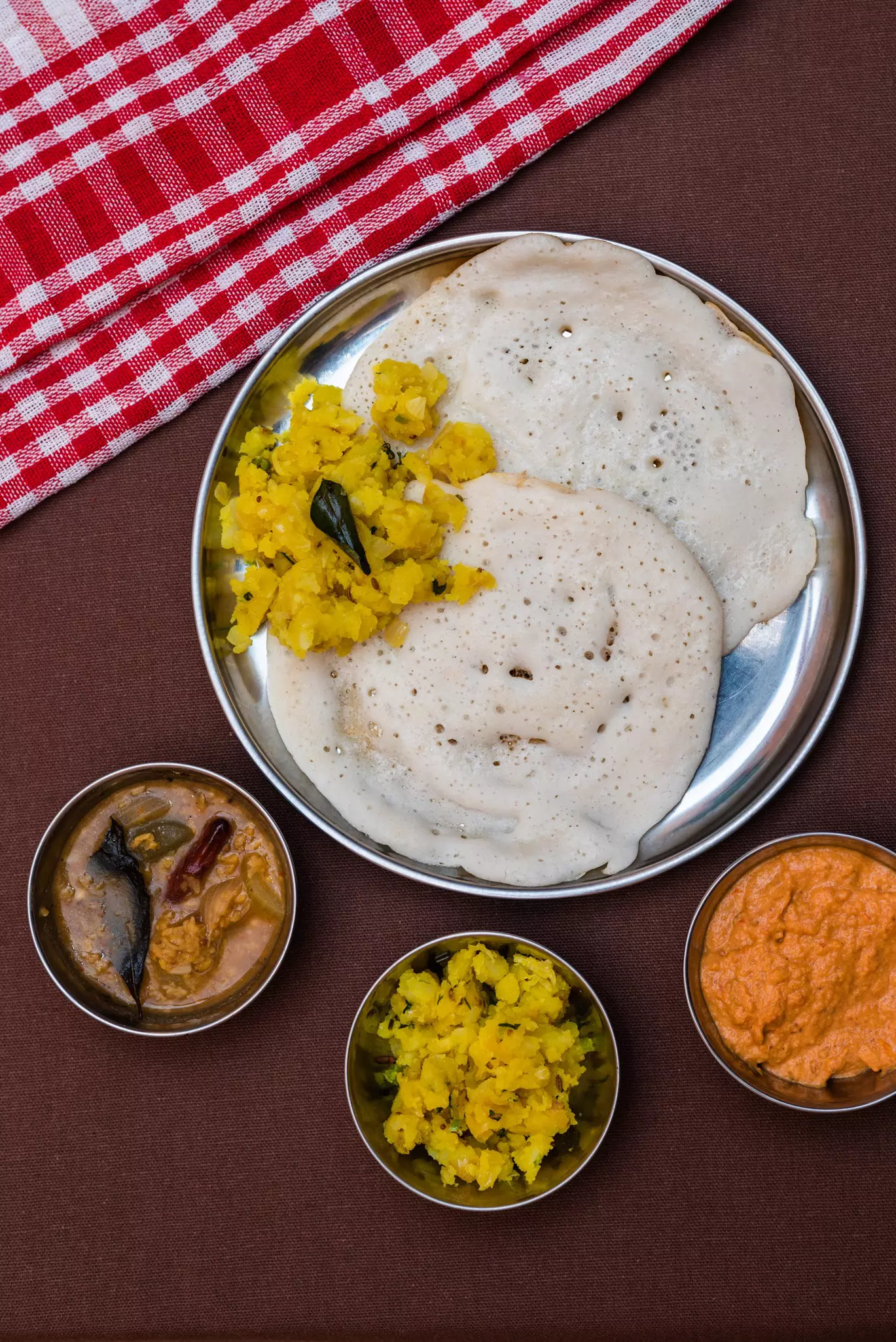 A main dish of pancakes served with a curried potato and small side dishes of sauces and vegetables.