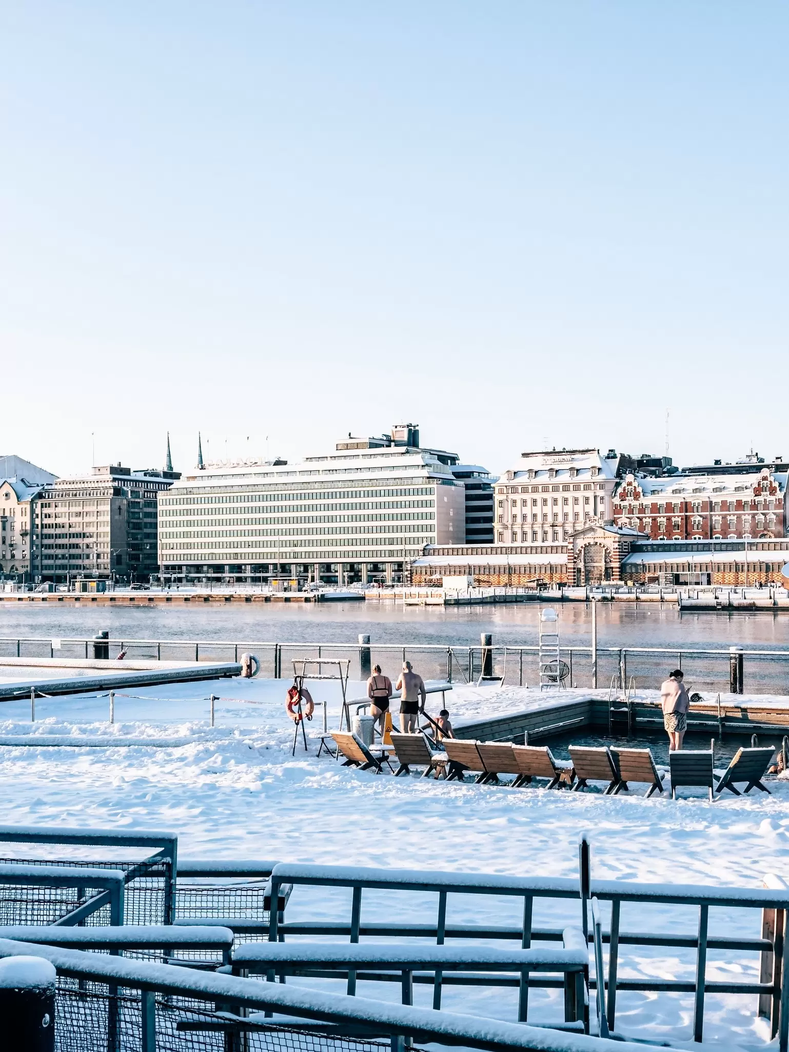 People at an outdoors city sauna that's surrounded by snow