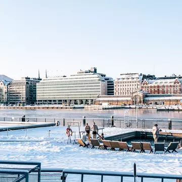 People at an outdoors city sauna that's surrounded by snow
