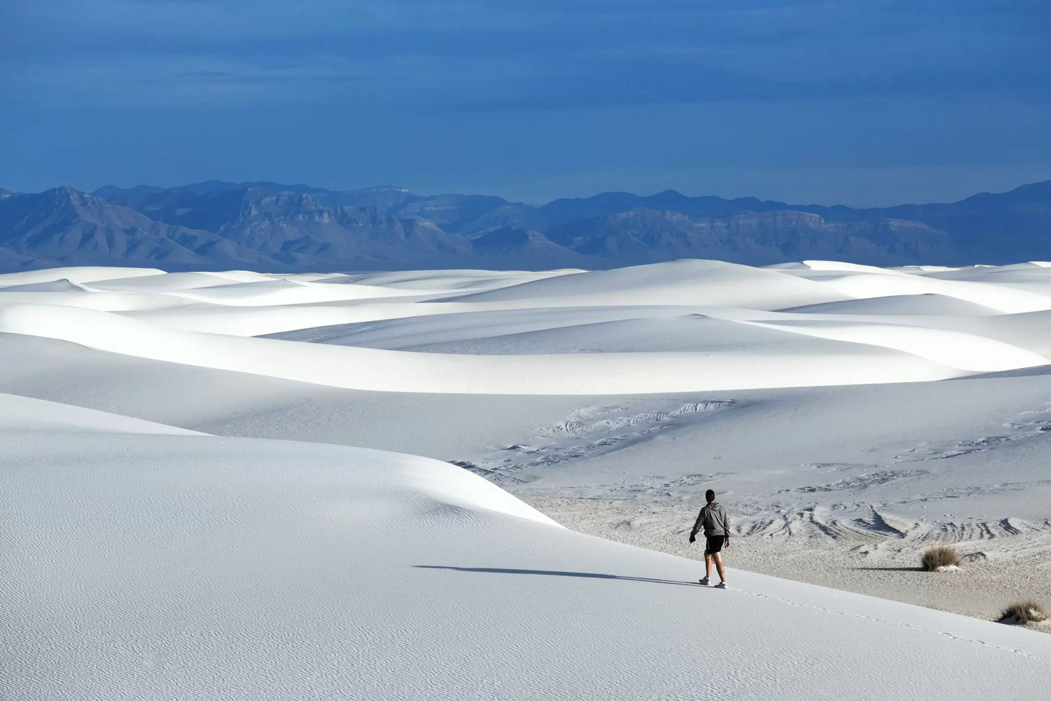 A hiker crosses dunes at White Sands National Park, New Mexico.