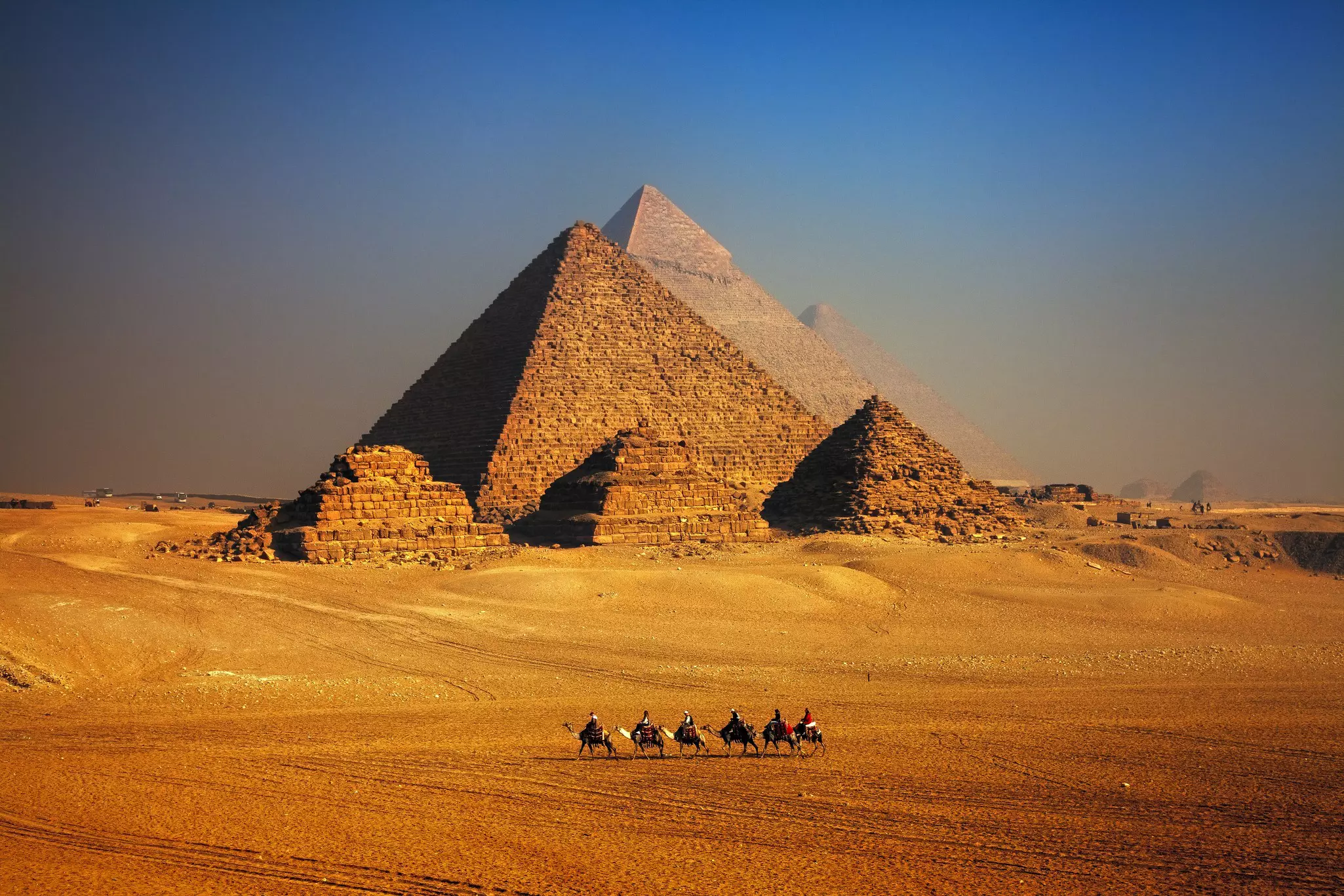 Pyramids of Giza and camel caravan in desert. ©Mark Brodkin Photography/Getty