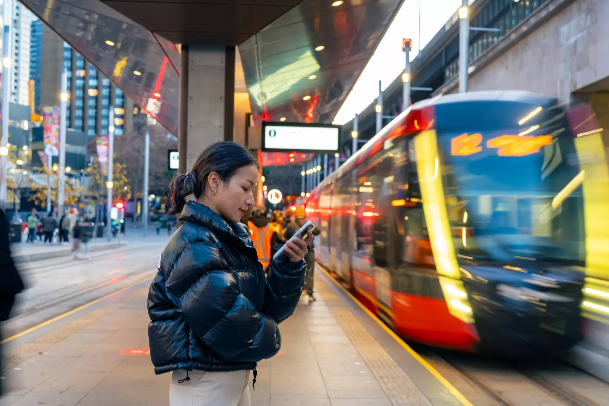 Happy Asian woman using mobile phone with mobile app chatting or social media during waiting for tram at station. Attractive girl enjoy urban outdoor lifestyle travel city street with smartphone.; Shutterstock ID 2328112699; purchase_order:65050 - Digital Destinations and Articles; job:Lonely Planet; client:How to get around in Sydney; other:Sasha Brady
2328112699