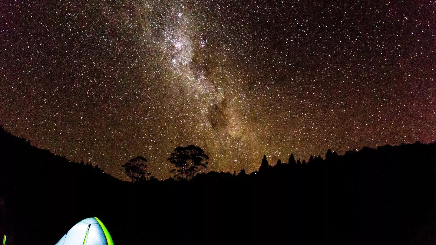 A tent under a brilliant night sky full of stars in New Zealand
