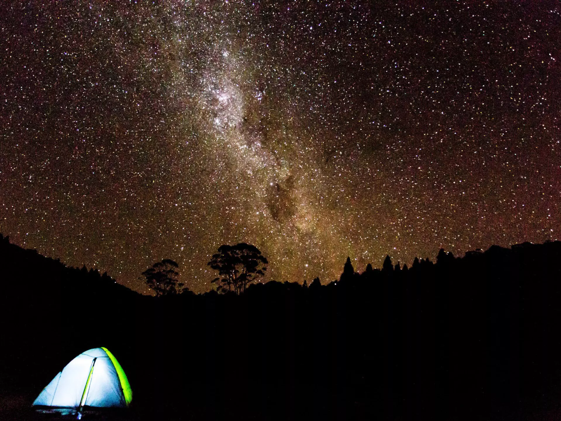 A tent under a brilliant night sky full of stars in New Zealand