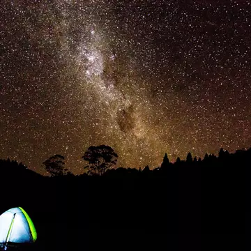 A tent under a brilliant night sky full of stars in New Zealand