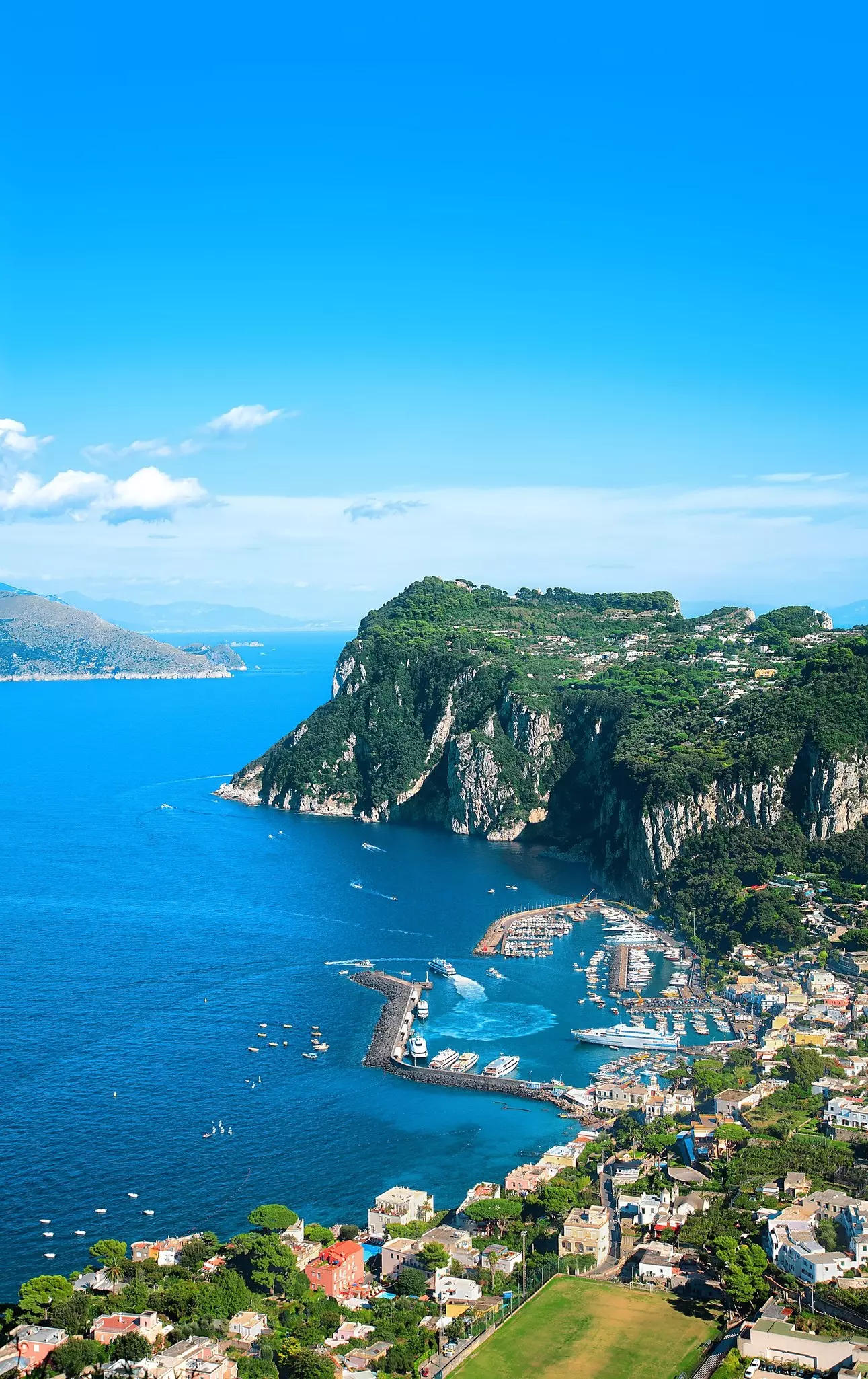 A ferry and several other boats docked in a harbor of a rocky island.