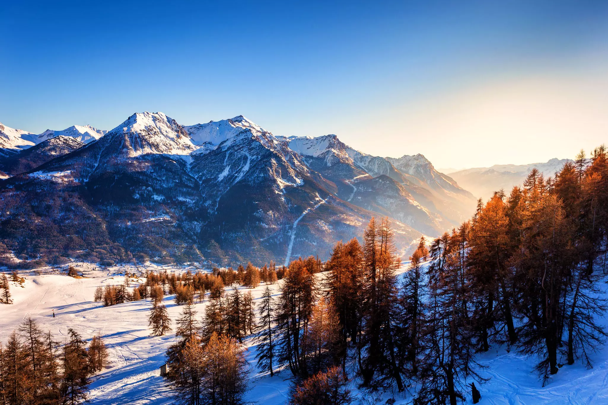 Frozen mountains near a ski resort with a blue sky just before sunset