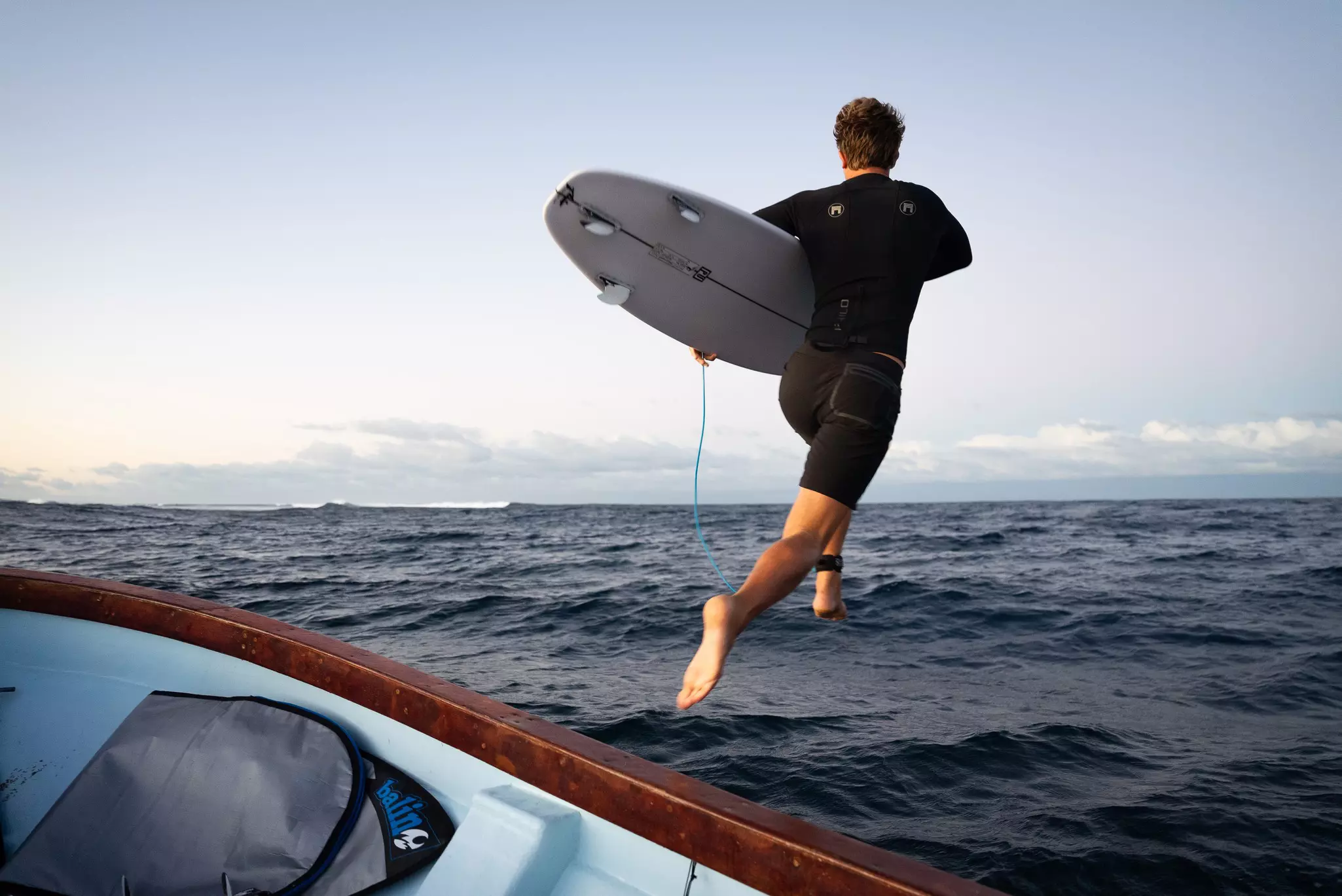 A surfer in Fiji jumping into the water with his board