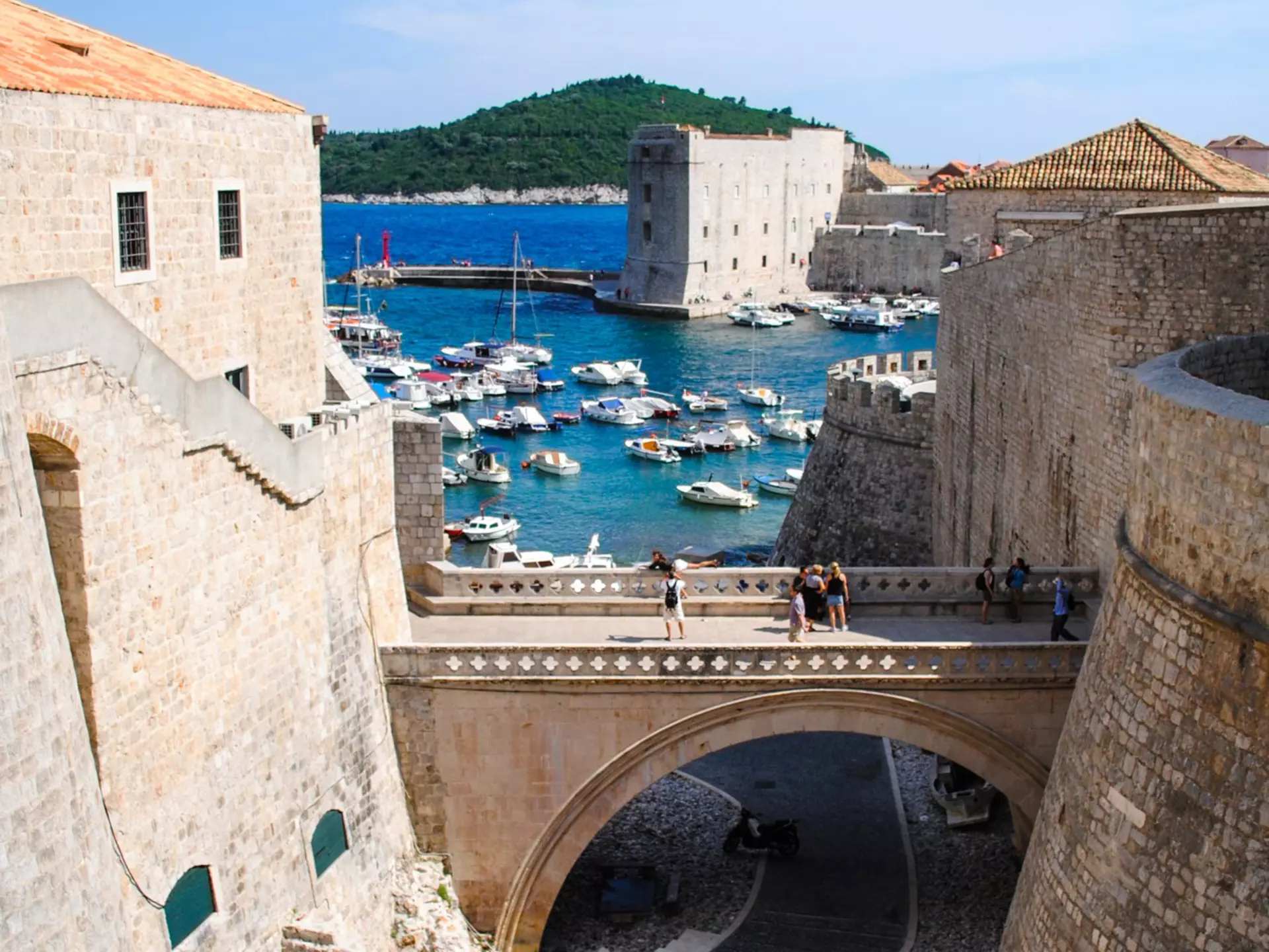 An ancient castle on the beach beckons tourists with its beauty and a view of blue waters beyond the stone buildings. 