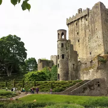 Exterior of Blarney Castle in Cork County, Ireland. Green grass and trees surrounding. 