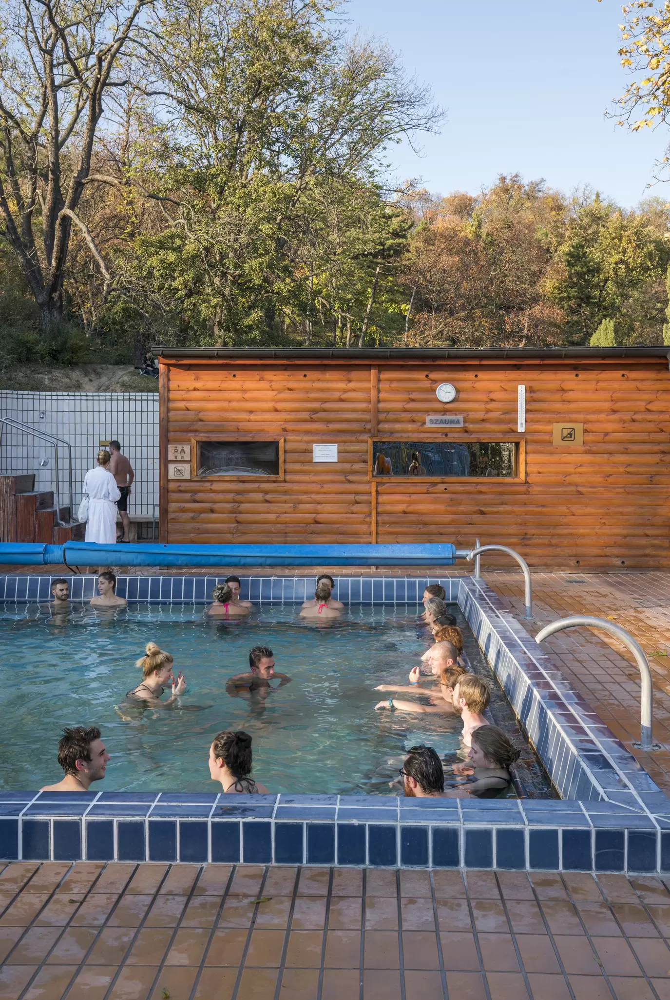 A group of people relax in an outdoor thermal bath.