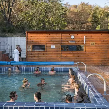 A group of people relax in an outdoor thermal bath.