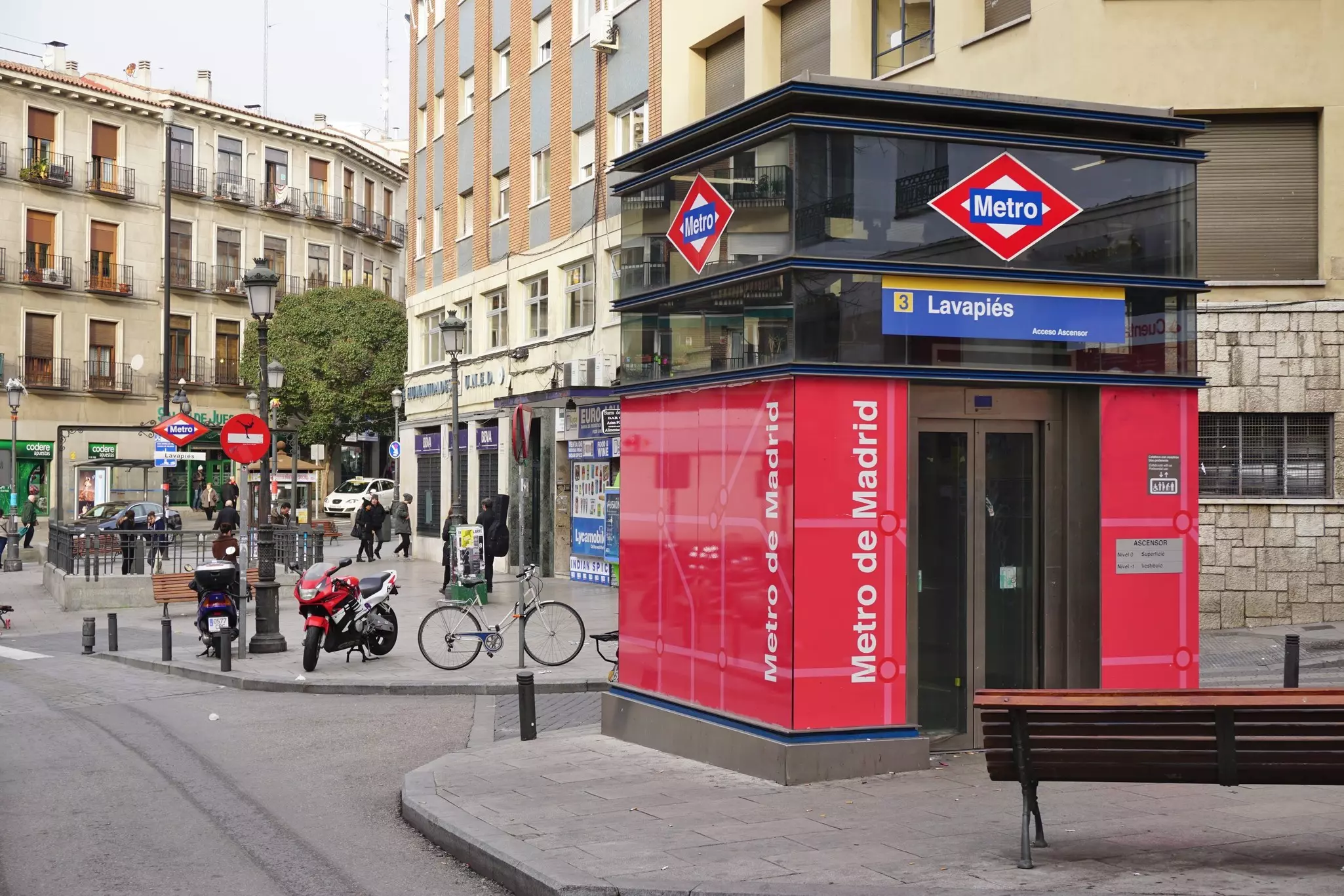 Red and blue sign reading "Metro de Madrid" at the entrance of the Lavapiés subway station on qa city street.