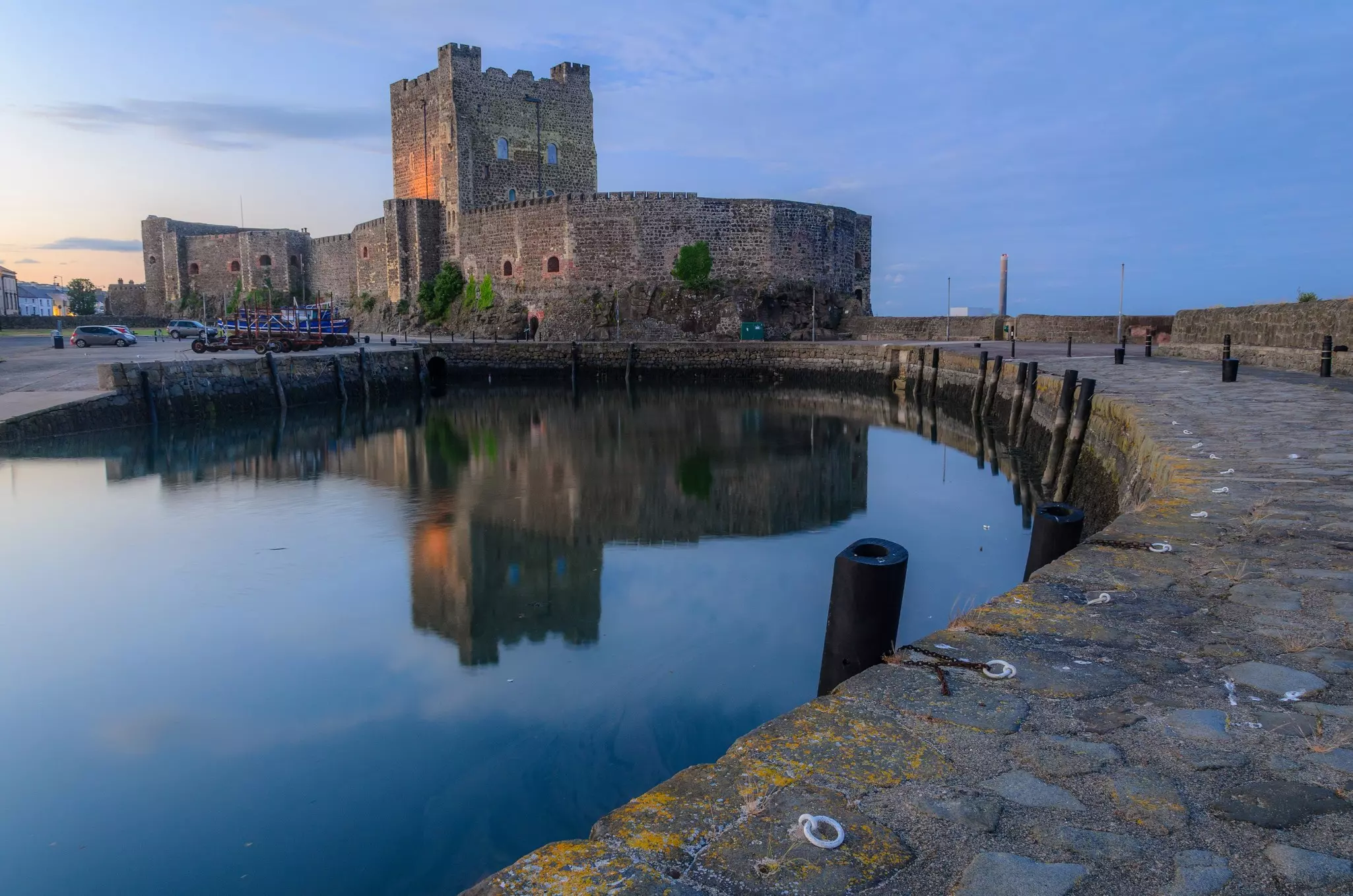 A stone path leading surrounding water leads up to a low-profile stone castle