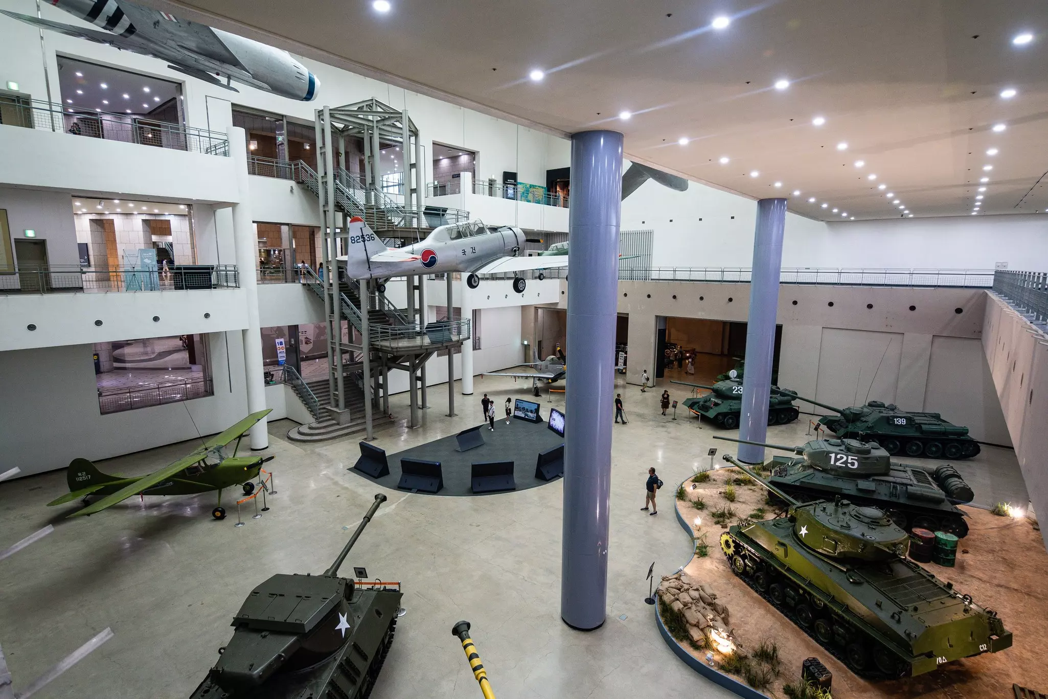 Tanks, warplanes and other military matériel is on display in a huge gallery of a museum.
