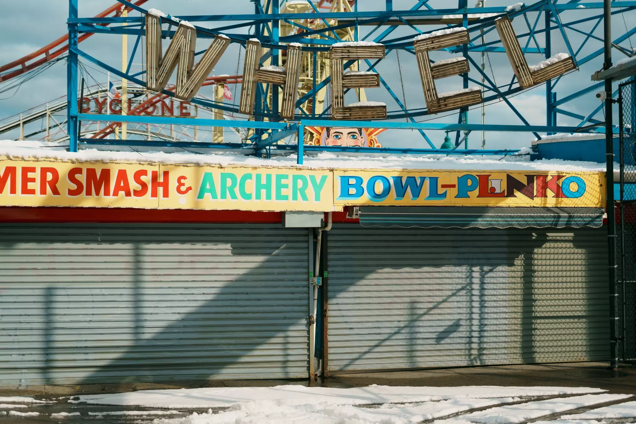 Vintage signs at Deno's Wonder Wheel Amusement Park in Coney Island, Brooklyn, New York. A thin layer of snow covers the ground.