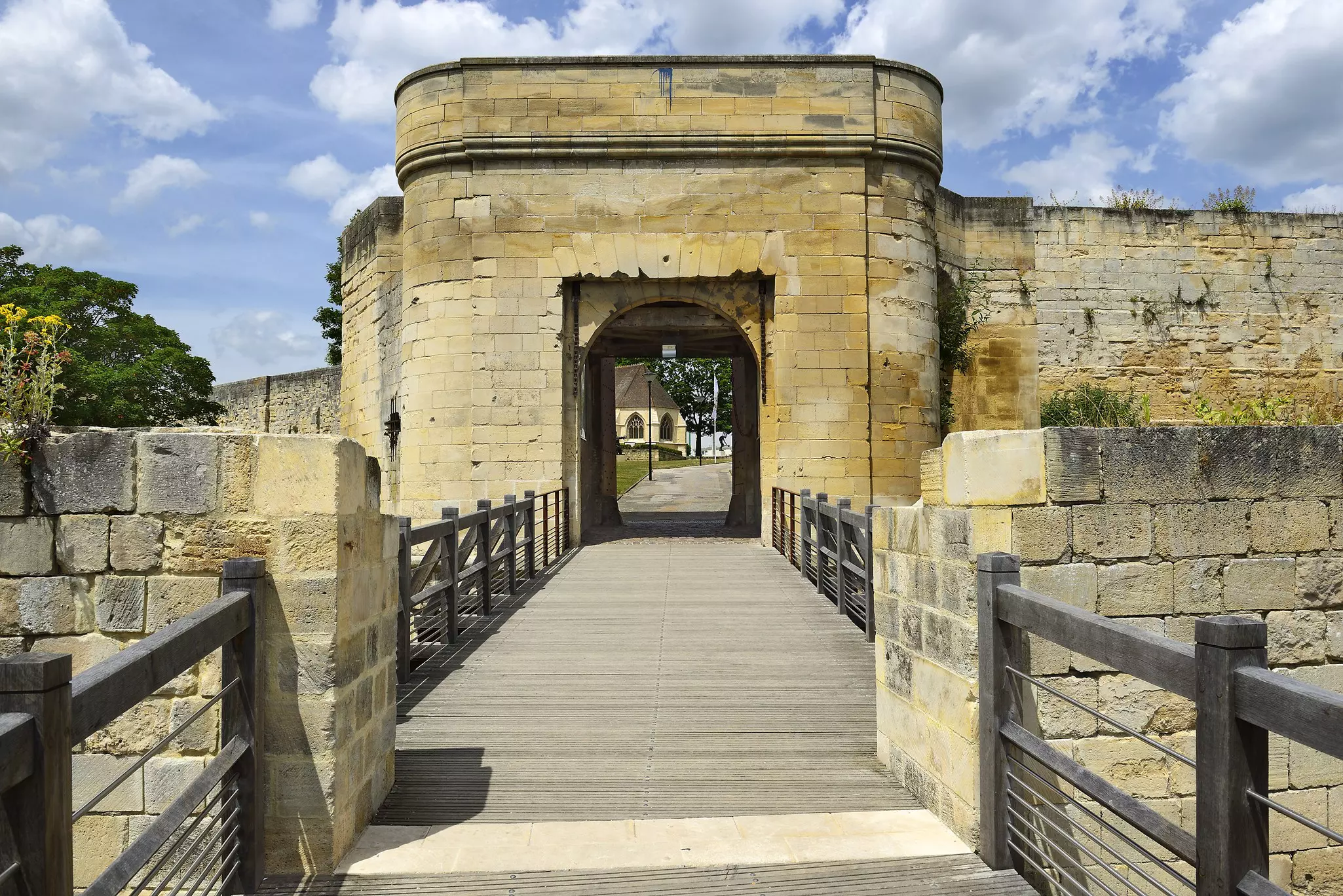 A wooden walkway leading through a stone arch at a medieval castle.