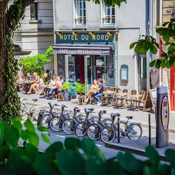 People eating and drinking on the terrace of the famous Hotel du Nord with bike share in the foreground