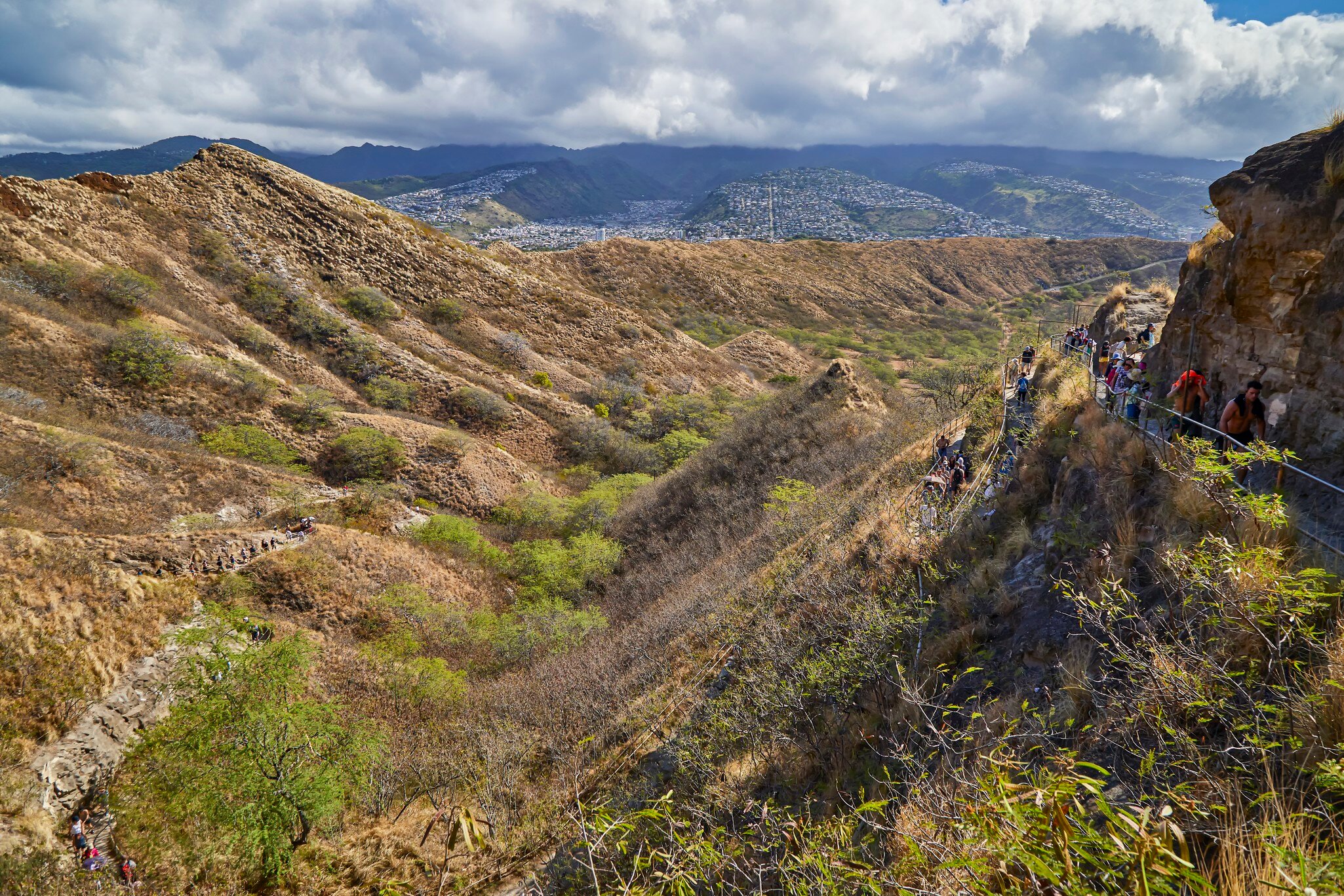 People walking along the walking path up and down to the top lookout of Diamond Head State Monument.