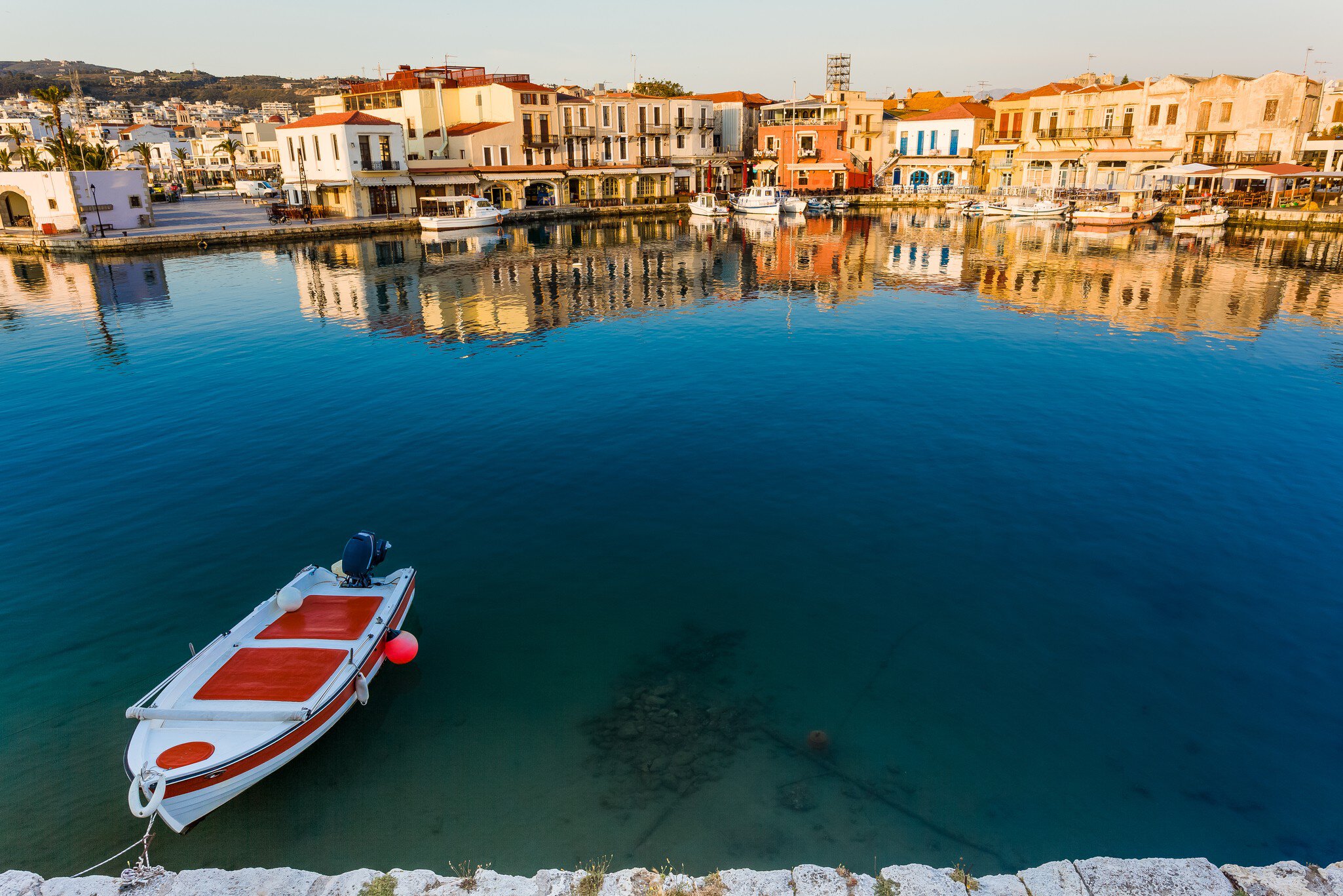 Fishing boat on canal in front of townscape, Rethymno, Crete, Greece