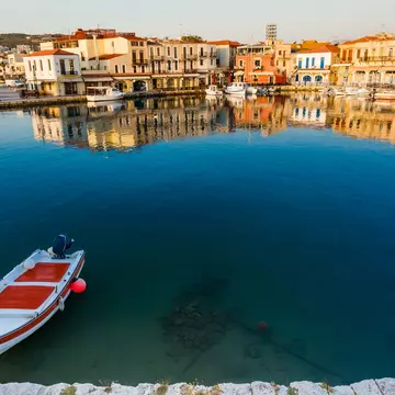 Fishing boat on canal in front of townscape, Rethymno, Crete, Greece