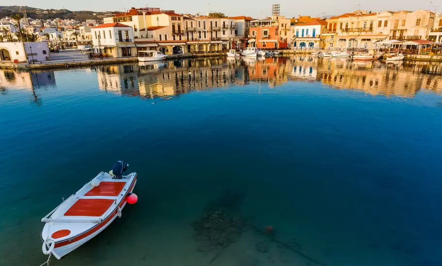 Fishing boat on canal in front of townscape, Rethymno, Crete, Greece
