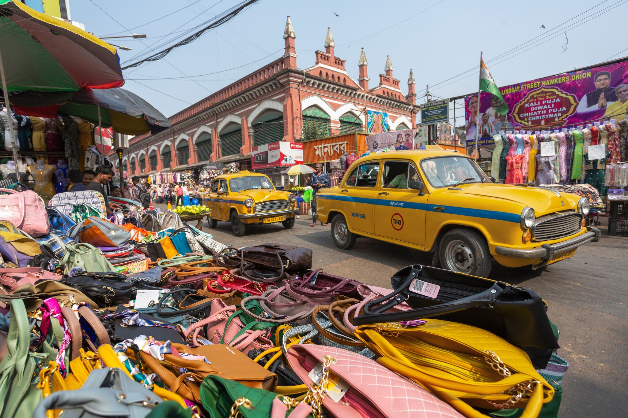 View from a market stall selling handbags in New Market, Kolkata, India. Taxi cabs driving past.