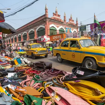View from a market stall selling handbags in New Market, Kolkata, India. Taxi cabs driving past.