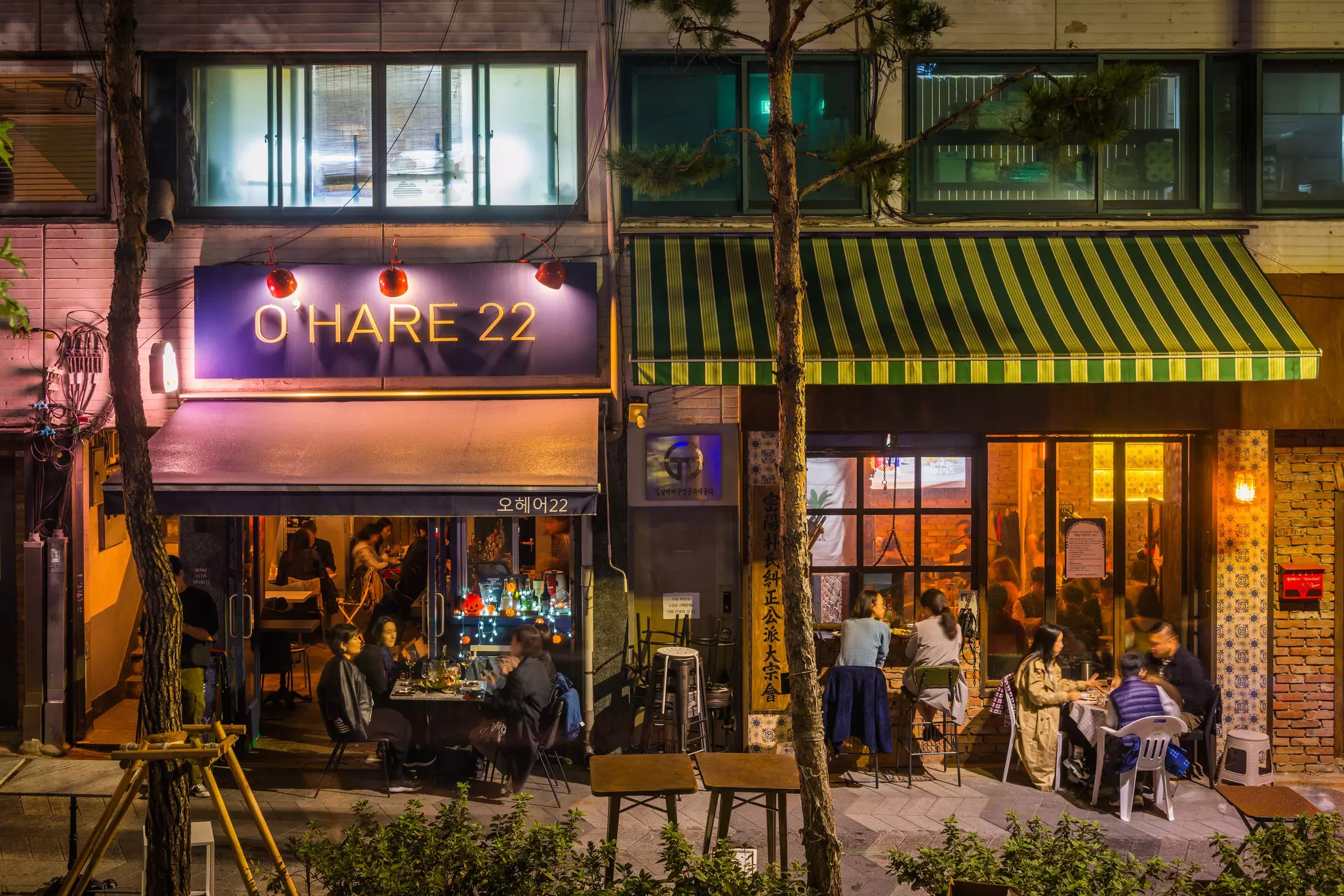 A street view of people inside and outside bars drinking at night in Seoul.