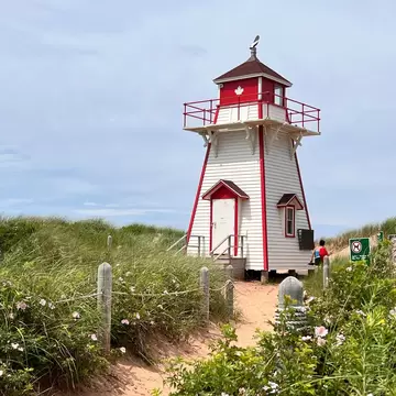 View of Covehead Harbour lighthouse, a red and white painted heritage lighthouse, standing amidst the dunes and grasses at Prince Edward Island National Park, Canada.  