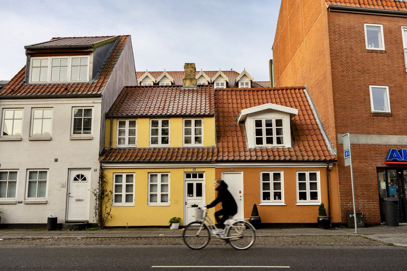 Cyclist biking past orange and yellow buildings in Aarhus, Denmark.