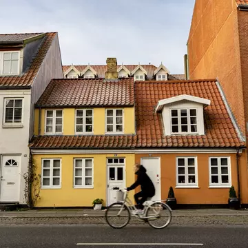 Cyclist biking past orange and yellow buildings in Aarhus, Denmark.