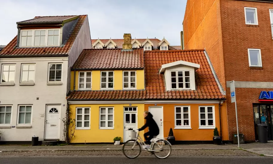 Cyclist biking past orange and yellow buildings in Aarhus, Denmark.