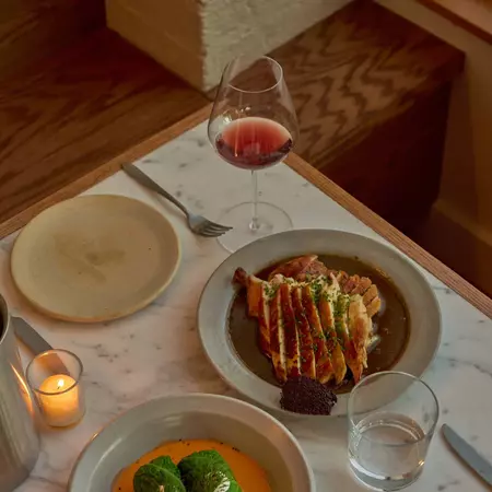 A placesetting with food and a partially filled wine glass 