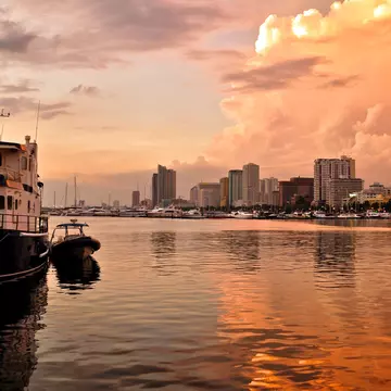 Skyline sit in golden reflective water at sunset.