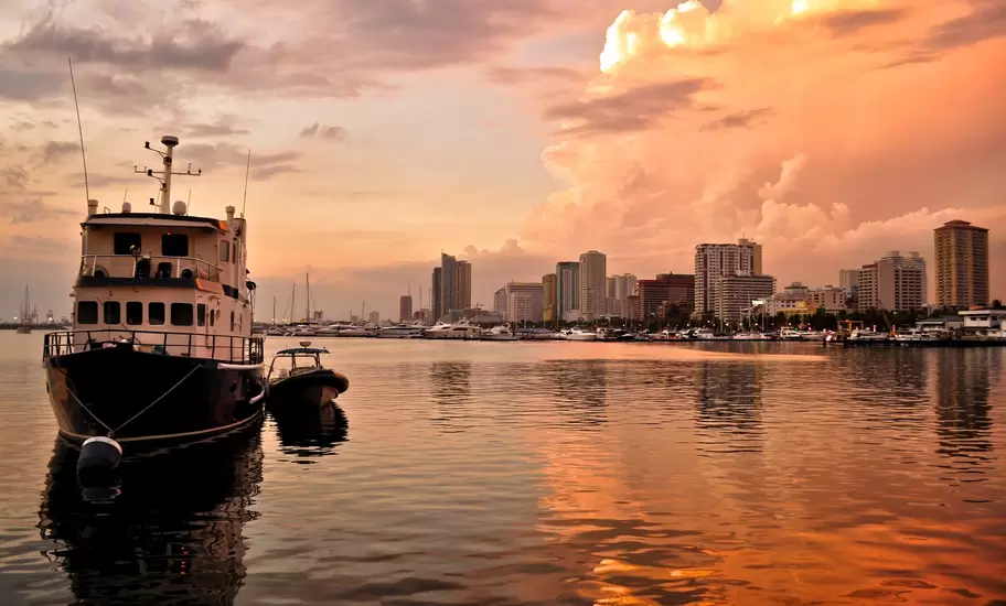 Skyline sit in golden reflective water at sunset.