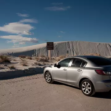 ALAMOGORDO, NEW MEXICO - DECEMBER 9, 2013: A 2013 silver 4-door Mazda 3 sedan Enterprise rental car, parked at the Backcountry Camping Loop parking area, at White Sands National Monument.  License Type: media  Download Time: 2023-09-01T03:35:18.000Z  User: aomi.ito_lonelyplanet  Is Editorial: Yes  purchase_order:   
