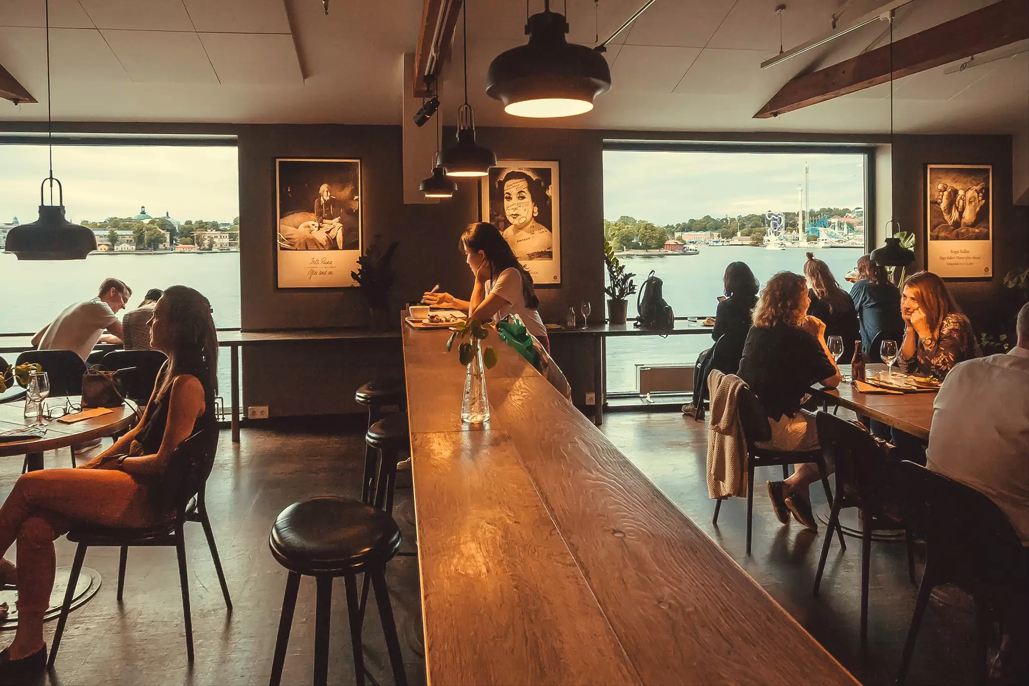 Groups of people sitting at tables in the restaurant at Fotografiska with views over the water.
