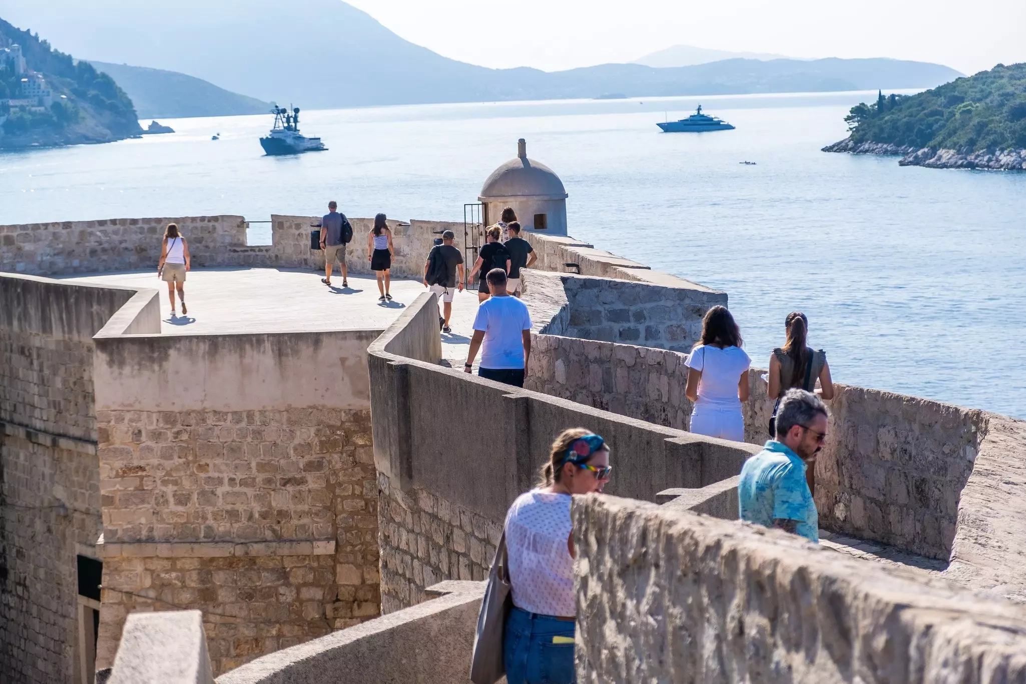 Visitors stroll along the historic Dubrovnik city walls with panoramic views of the Adriatic Sea. Ivan Klindic/Shutterstock