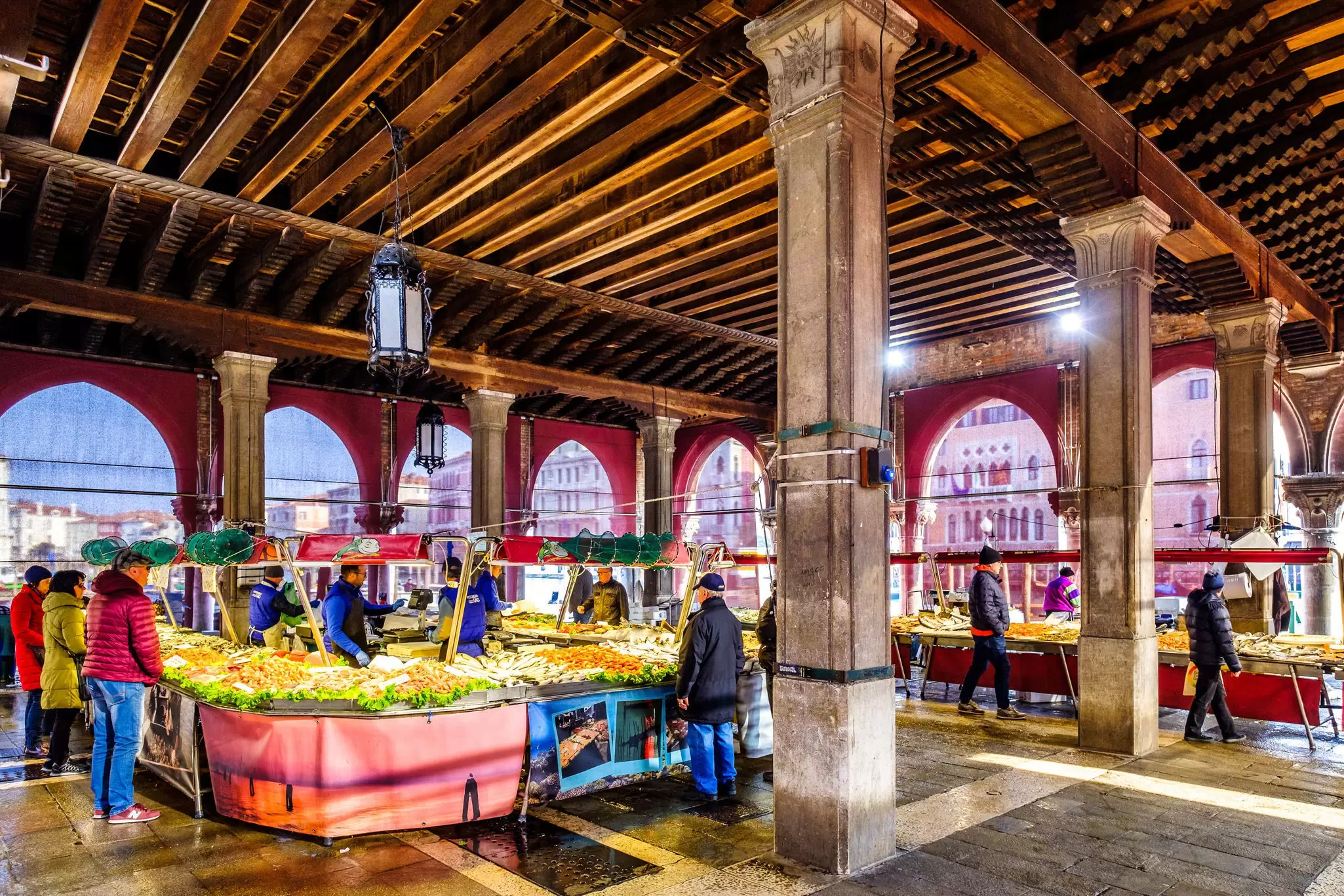 Shoppers by stalls selling fish at the Rialto Market in Venice, Italy.