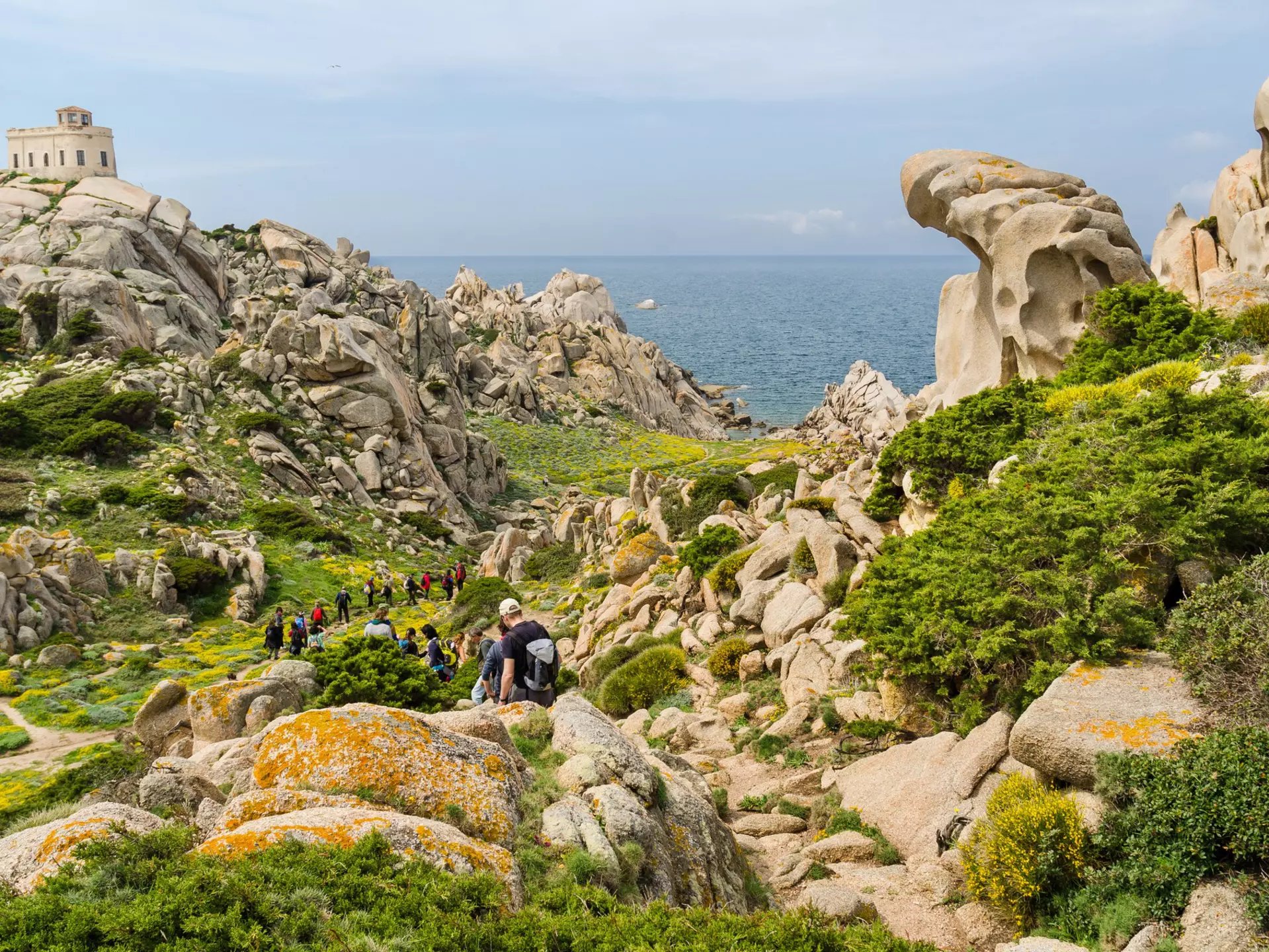 Hikers follow a coastal trail through boulders