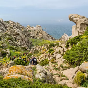 Hikers follow a coastal trail through boulders