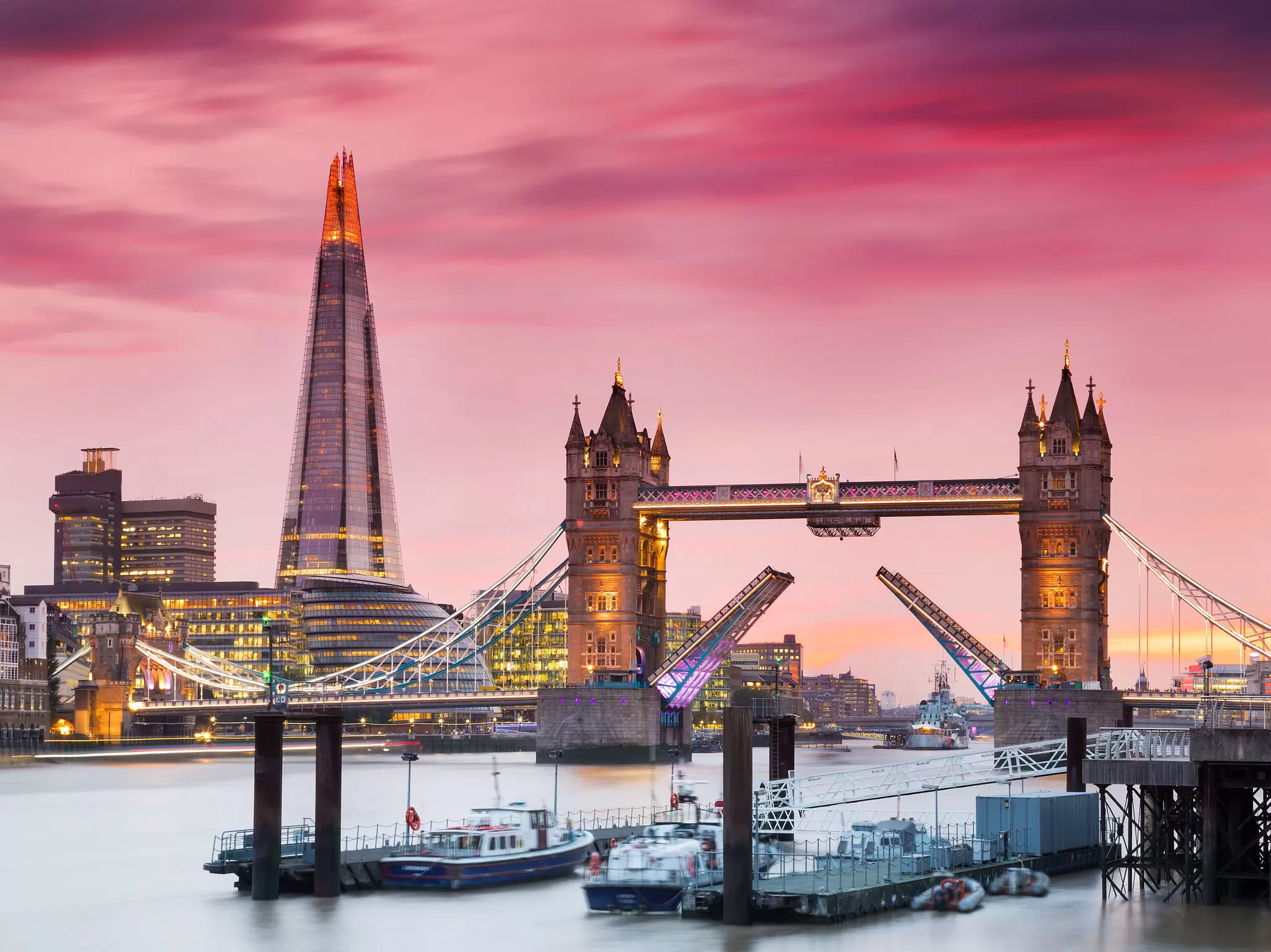 A bridge with two Gothic towers and a roadway opening in the center at sunset
